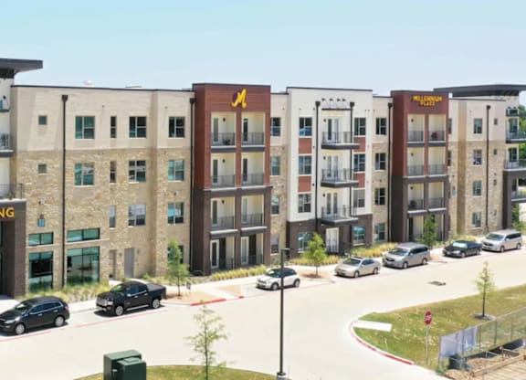 Apartment buildings with cars parked in front.