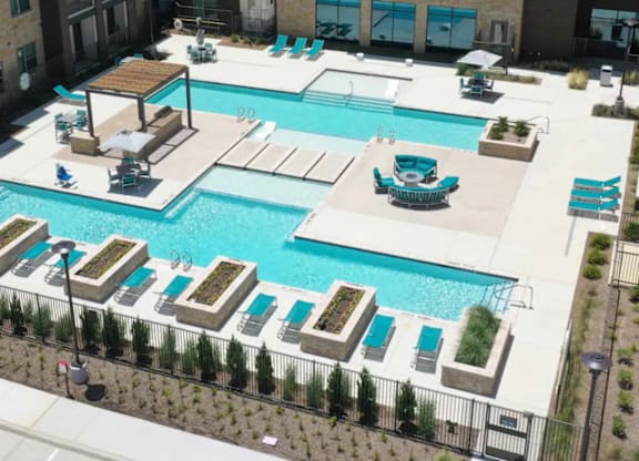 A large swimming pool surrounded by lounge chairs and umbrellas.