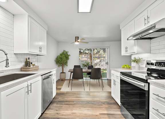 A modern kitchen with white cabinets and black appliances.
