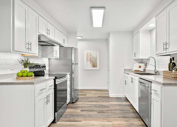 A modern kitchen with white cabinets and stainless steel appliances.
