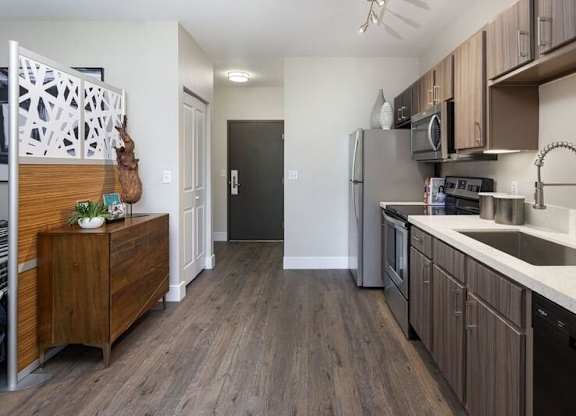 A kitchen with wooden floors and a black refrigerator.