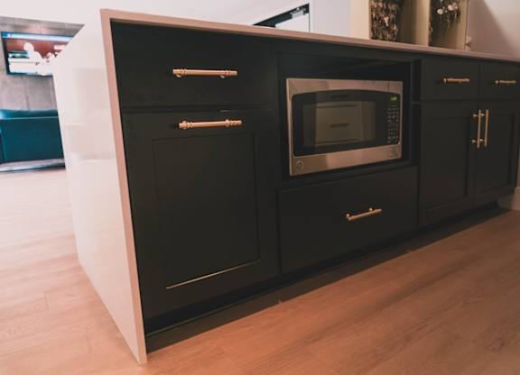 A black microwave oven is built into a black cabinet.