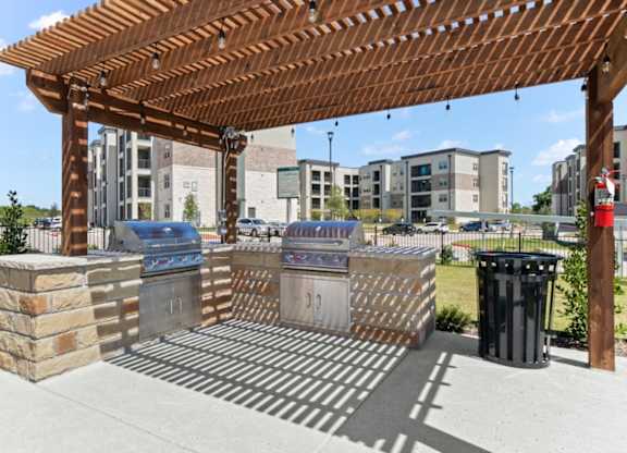 A wooden pergola with a trash can and a fire hydrant.