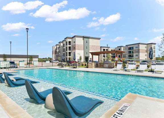 A pool with blue chairs and a building in the background.