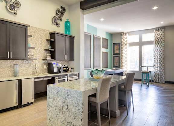 A kitchen with a marble island and a dining table with chairs.