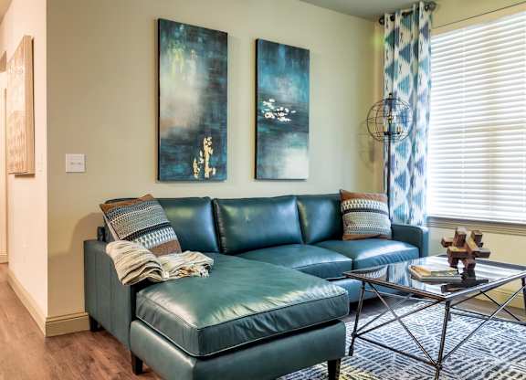 A living room with a blue couch and two paintings on the wall.