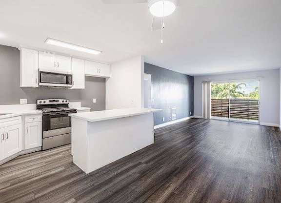 A kitchen with white cabinets and a wooden floor.
