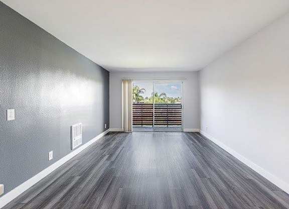 A room with grey walls and wooden flooring with a window and a door.