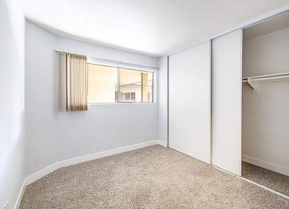 A room with a carpeted floor and a window with blinds.