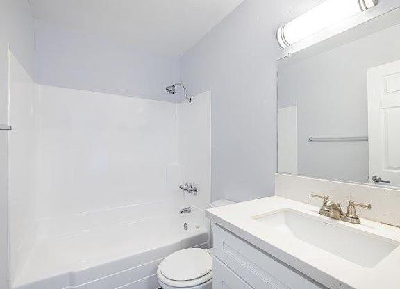 A white bathroom with a toilet, sink, and shower.