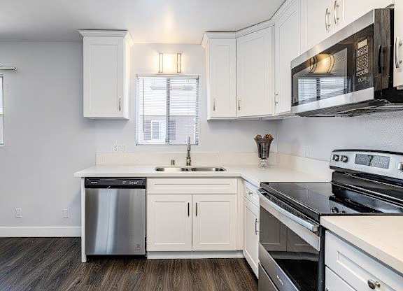 A kitchen with white cabinets and black appliances.