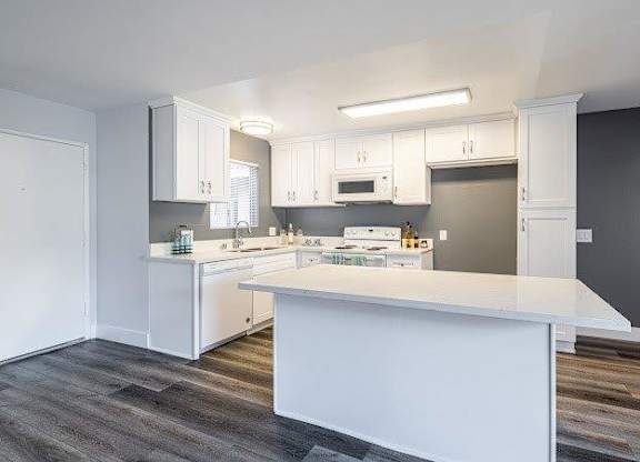 A kitchen with white cabinets and a white island.