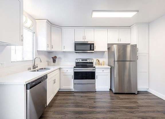 A kitchen with white cabinets and a stainless steel refrigerator.