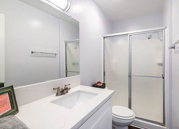 A white bathroom with a toilet, sink, and shower.