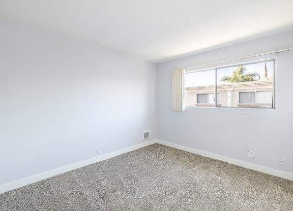A room with a window showing a building outside.