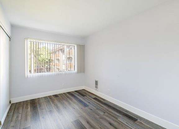 A room with a window and wooden flooring.