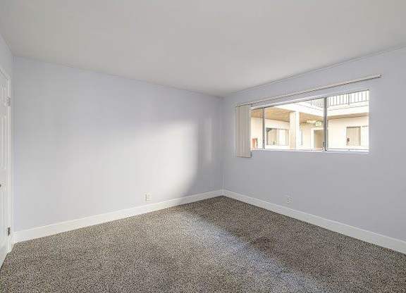 A room with a carpeted floor and a window letting in sunlight.