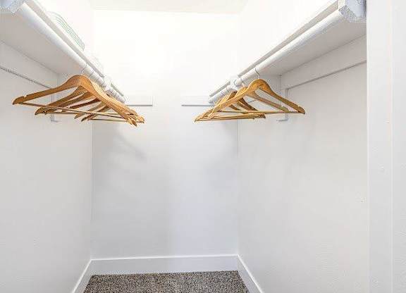 Two wooden hangers are hanging on a white wall.
