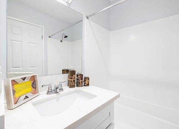A white bathroom with a sink and a mirror.