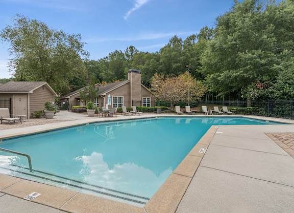 A swimming pool surrounded by trees and a house.