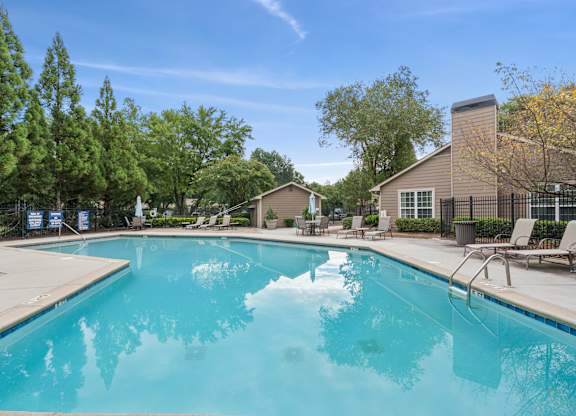 A large swimming pool surrounded by trees and chairs.