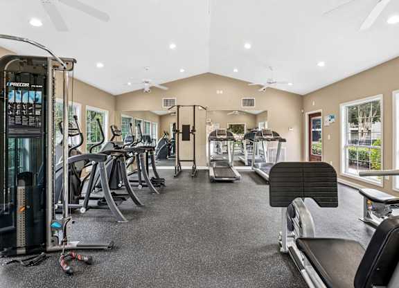 A spacious gym with a variety of equipment including treadmills, elliptical machines, and a weight machine.