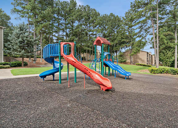 A playground with a red slide and blue slide.
