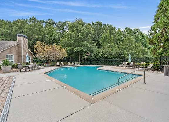 A swimming pool surrounded by trees and a house.