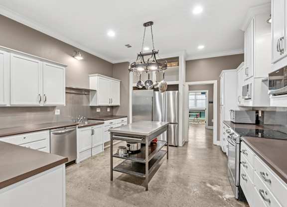 A large, empty kitchen with stainless steel appliances and white cabinets.