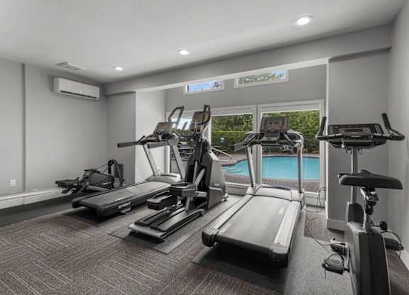 a gym with cardio equipment and a swimming pool
