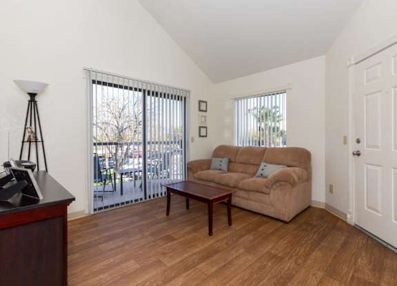 A living room with a tan couch and a wooden floor.