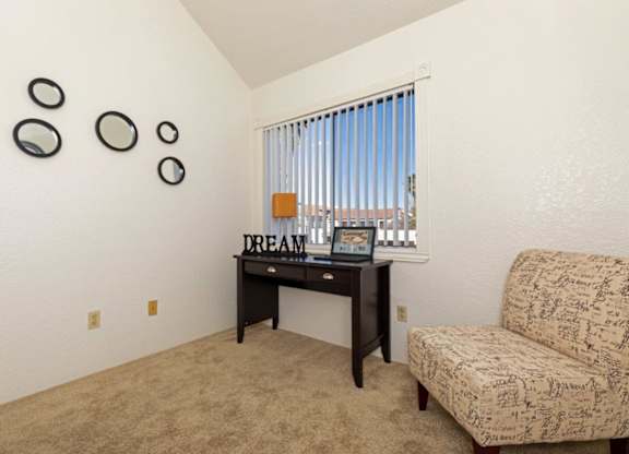 A room with a desk, chair, and mirrors on the wall.