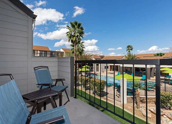 A patio with chairs and a pool in the background.