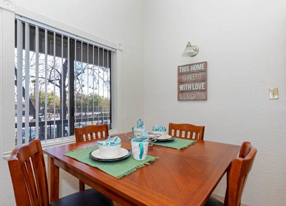 A dining table set with a green placemat and a sign on the wall that says "This home is filled with love and laughter".