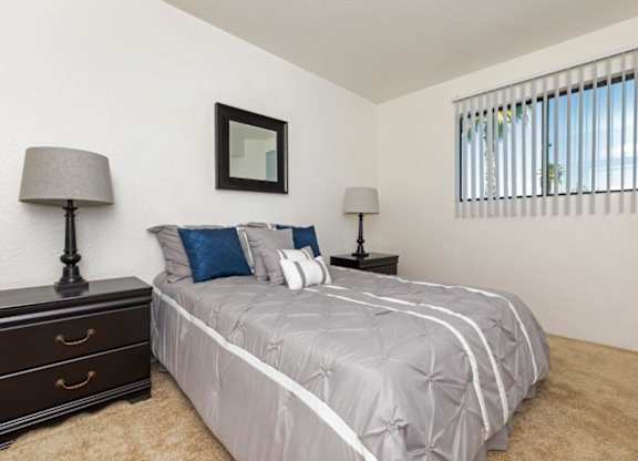 A bedroom with a bed, two lamps, and a picture on the wall.