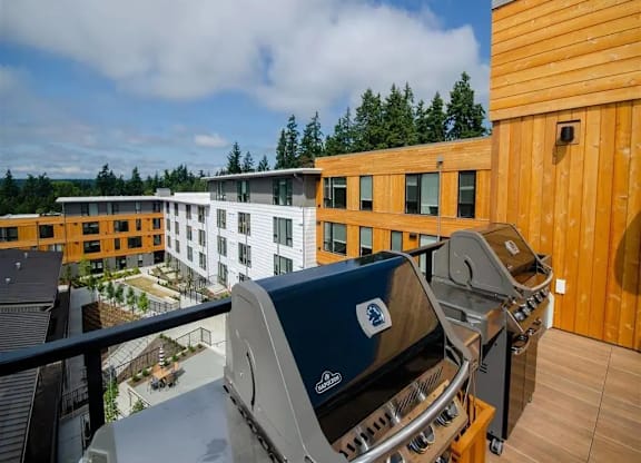A grill is on a balcony overlooking a white building.
