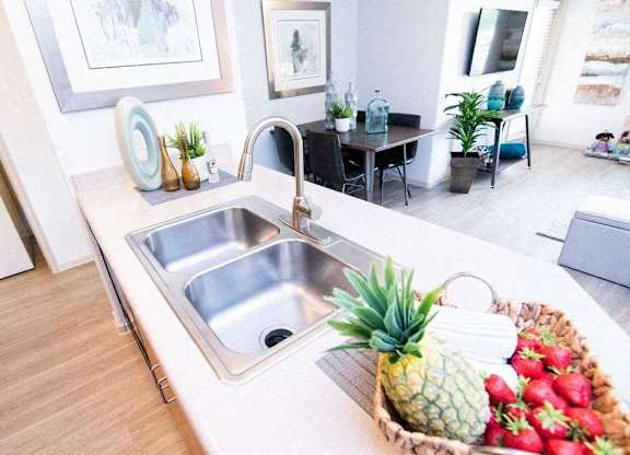 a kitchen sink with a pineapple and a basket of fruit