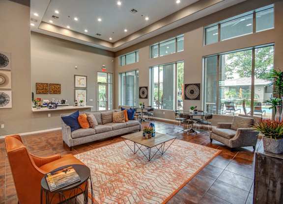 a living room with couches and chairs and large windows