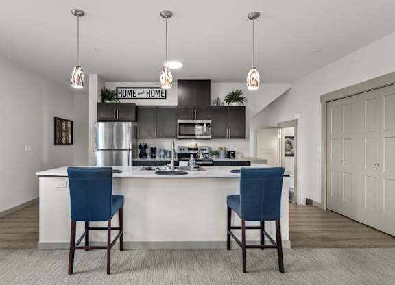 A kitchen with a white counter and blue chairs.