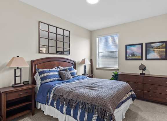 A bedroom with a bed, nightstand, and lamp.