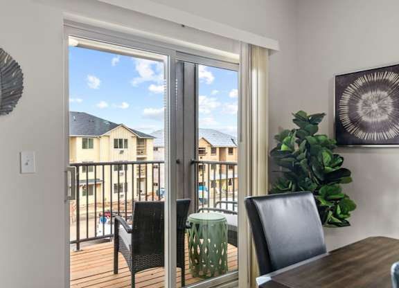 A dining room with a table and chairs and a view of a balcony.