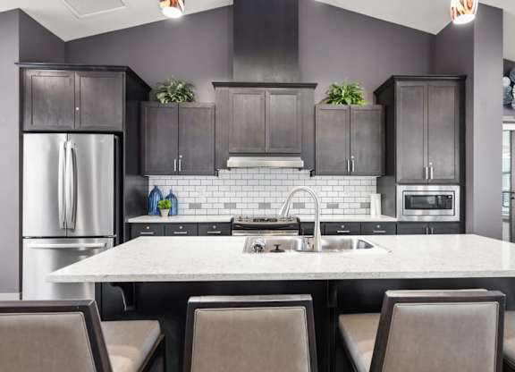 A modern kitchen with a large island and dark cabinets.