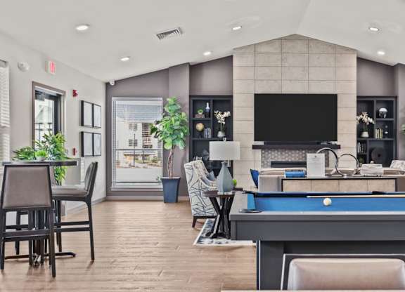 A well-lit room with a pool table and a television.
