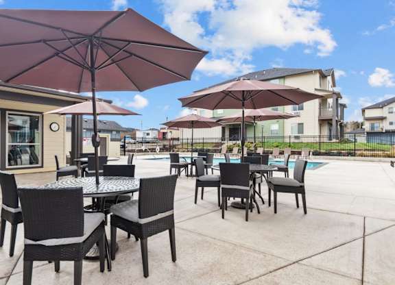 A patio with tables and chairs under umbrellas.