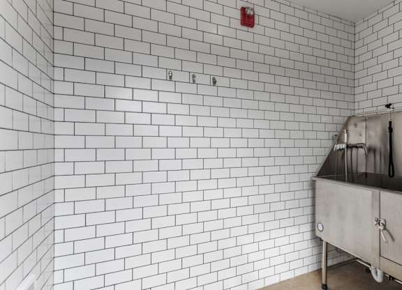 A white tiled wall with a red fire alarm on it.