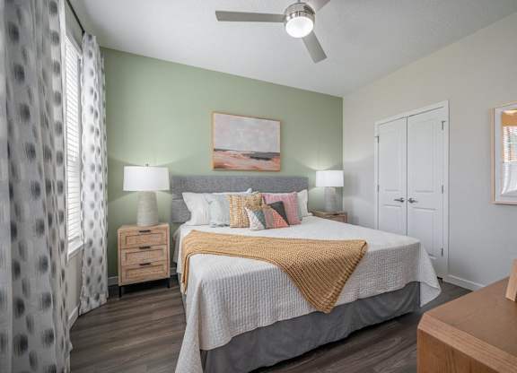 A bedroom with a bed, nightstands, and a ceiling fan.