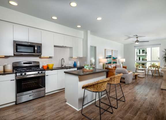 A modern kitchen with a wooden floor and white cabinets.
