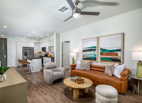 A living room with a brown couch, a wooden coffee table, and a painting on the wall.