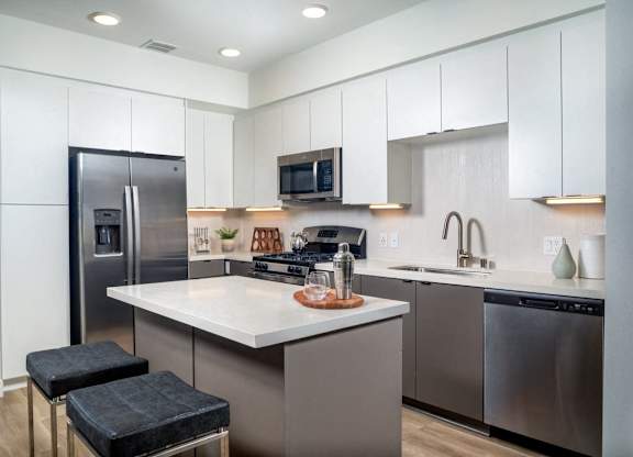 A modern kitchen with a stainless steel refrigerator and a white countertop.
