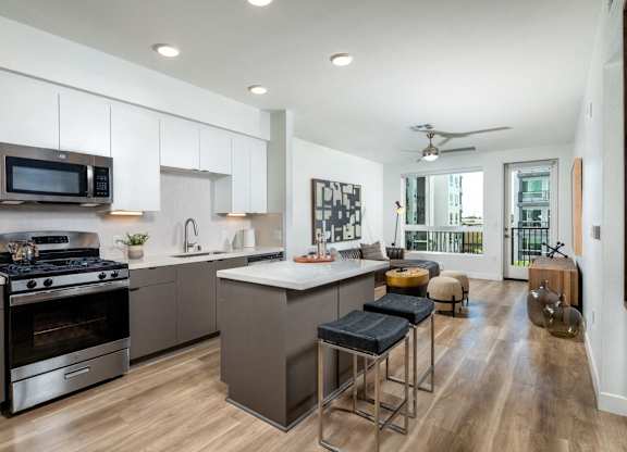 A modern kitchen with a stove, oven, and bar stools.